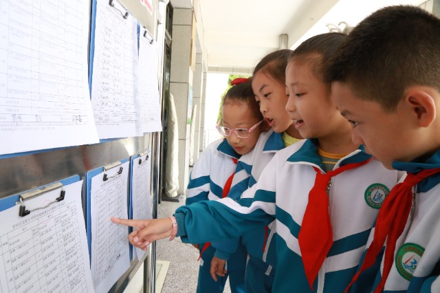 甘州區北街小學孩子在圍觀公示出的作業清單（張儒泰攝）.JPG
