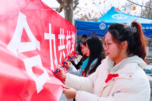 20231127中國石油大學（華東）青年學子在合力共抗艾滋的條幅上簽字，表達抗擊艾滋病的決心和信心  .jpg