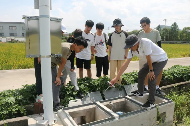 寧波財經學院“數智賦能鄉村”暑期社會實踐團成員在田間調試安裝設備 學校供圖.jpg